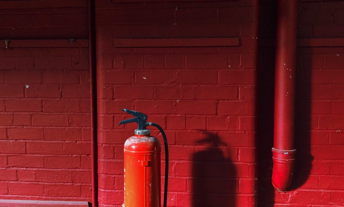 Fire extinguisher against red brick wall